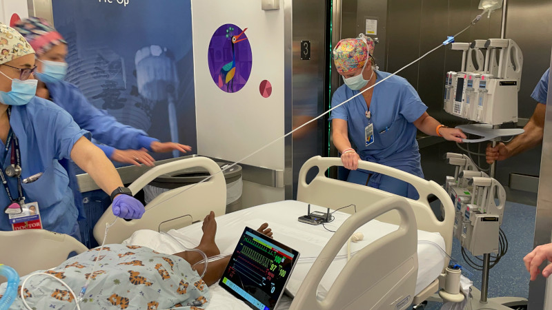 Clinicians wheel patient into sim operating room