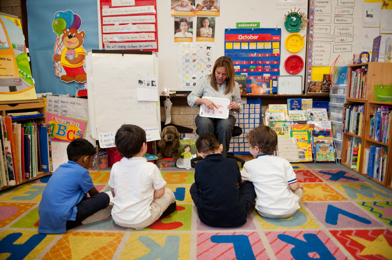 Woman reads to students sitting on the floor