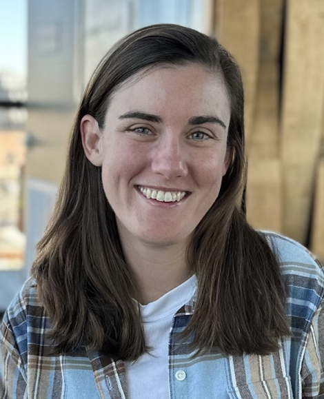 A woman with brown hair, Bridget Nestor, poses outside for her pain and stress studies team headshot.