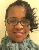 Stephanie Jones, a black woman wears glasses and has her hair up in a ponytail for her headshot.